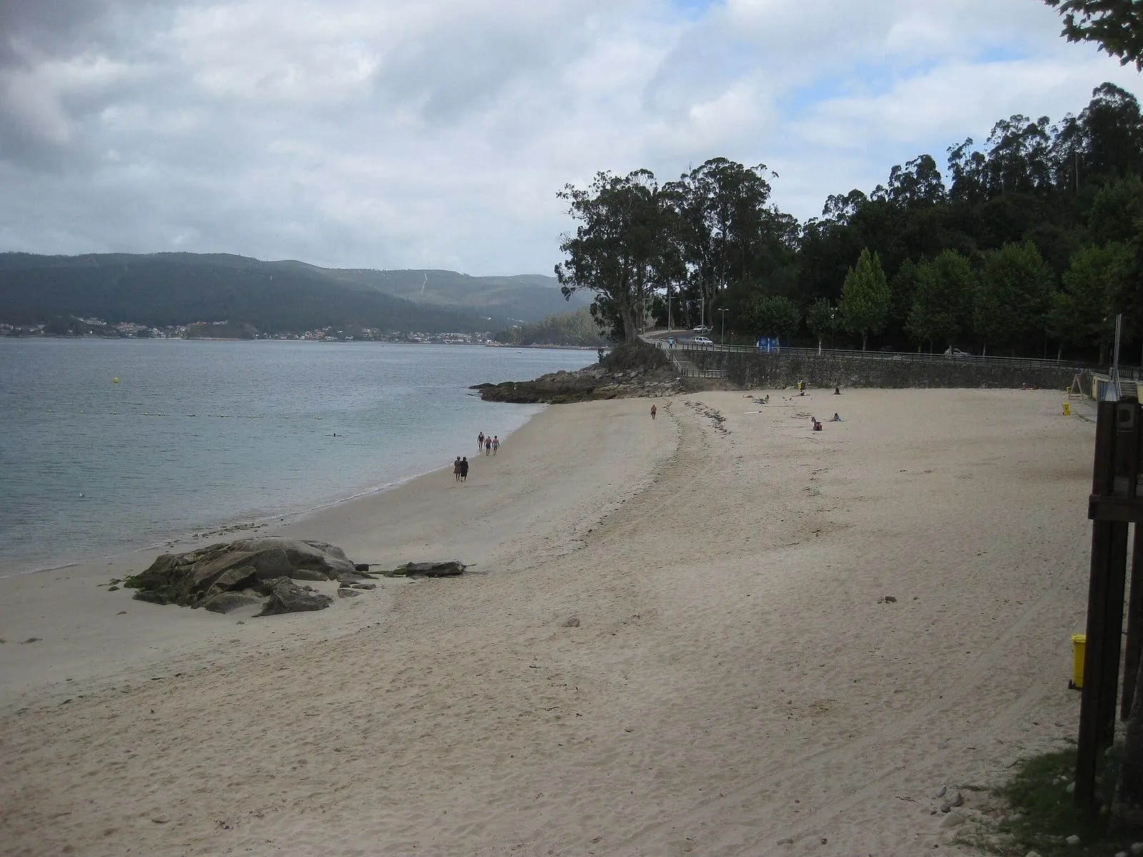 La playa de Portocelo, de arena clara, con una pequeña peña y la ría de Pontevedra al fondo