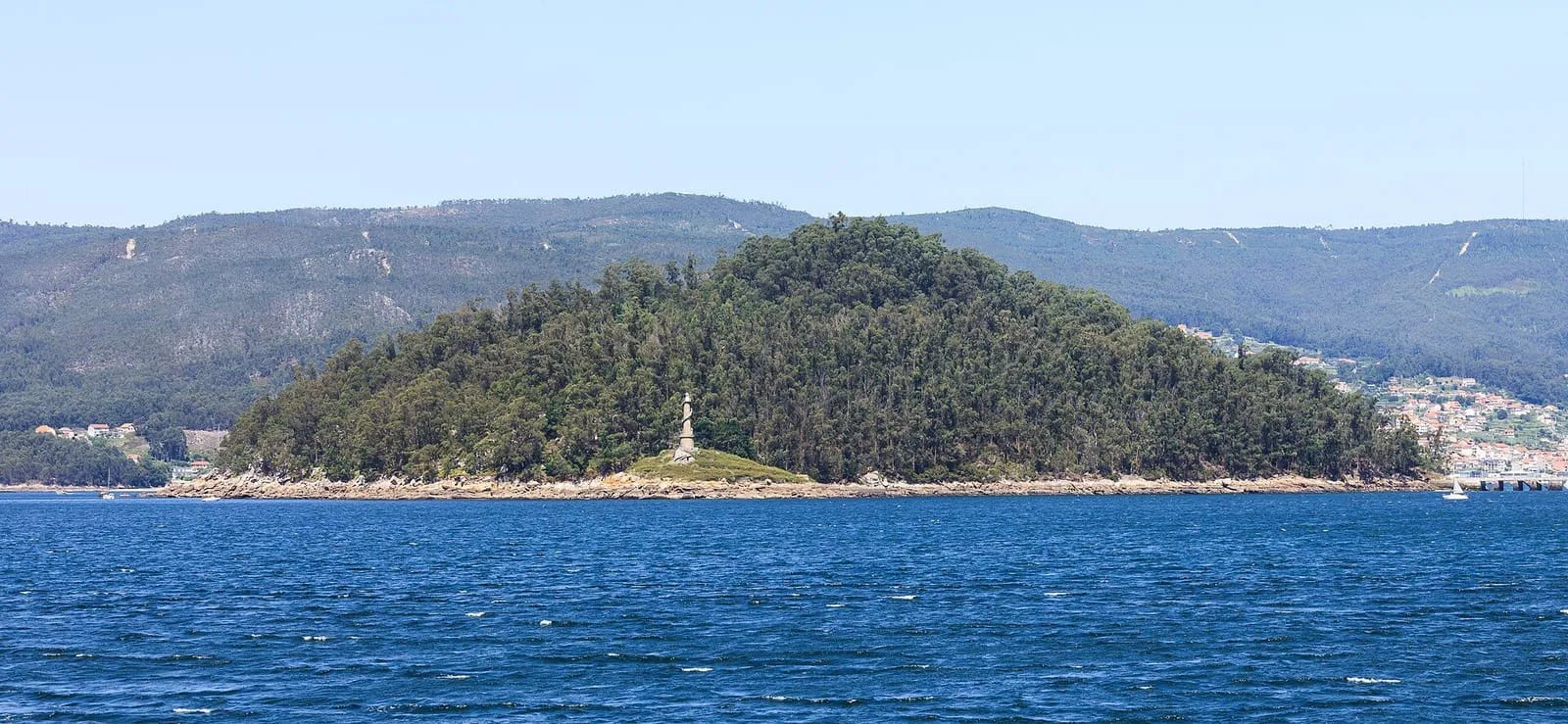 La isla de Tambo, un islote boscoso en la ría de Pontevedra con una torre blanca en su extremo