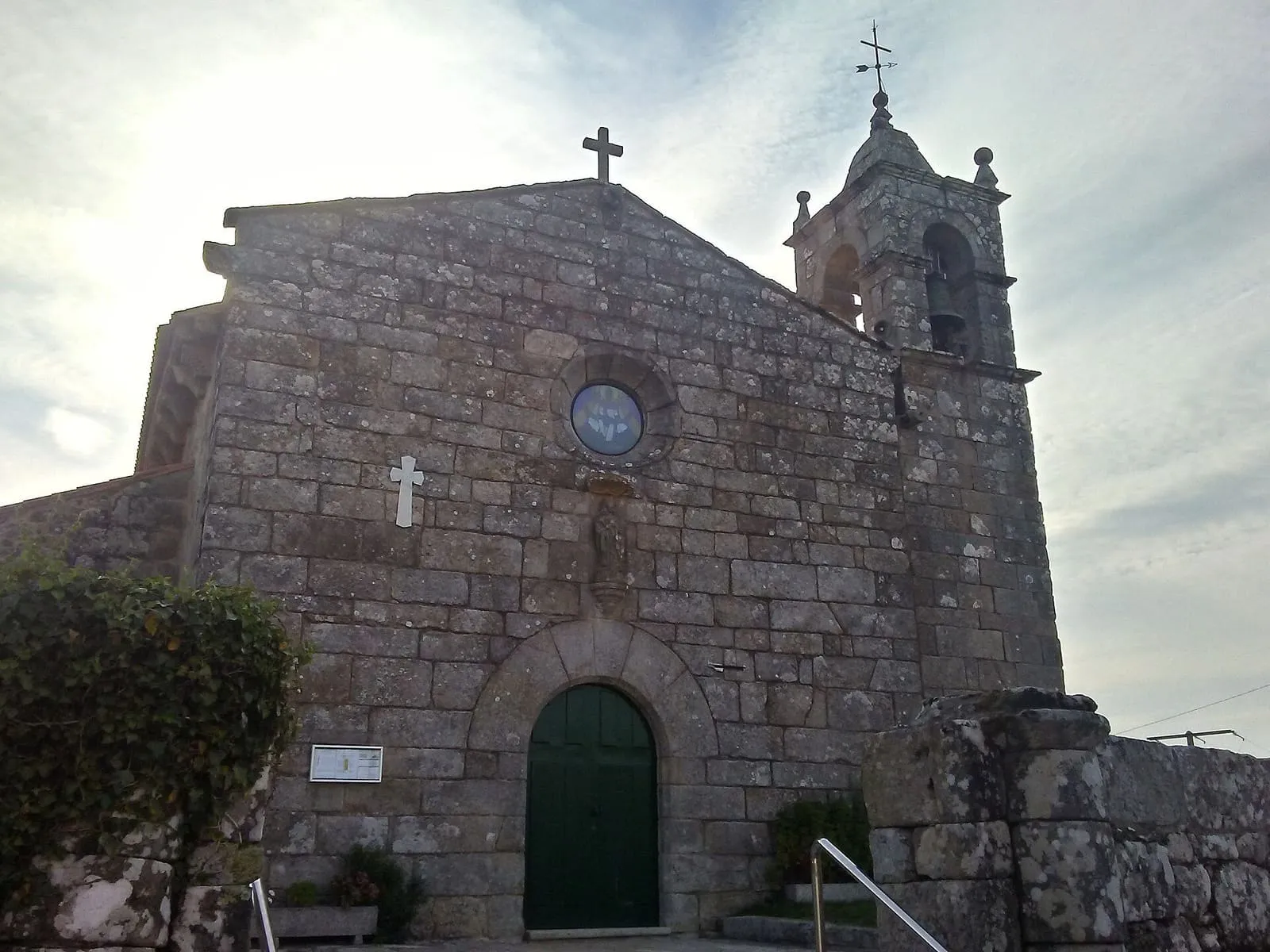 La iglesia de Santa María de Adina, de piedra, con su campanario de pináculos y la puerta de medio punto