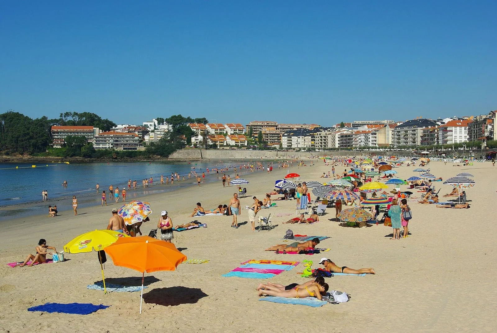 Playa de Silgar con sombrillas y la línea de casas de Sanxenxo al fondo