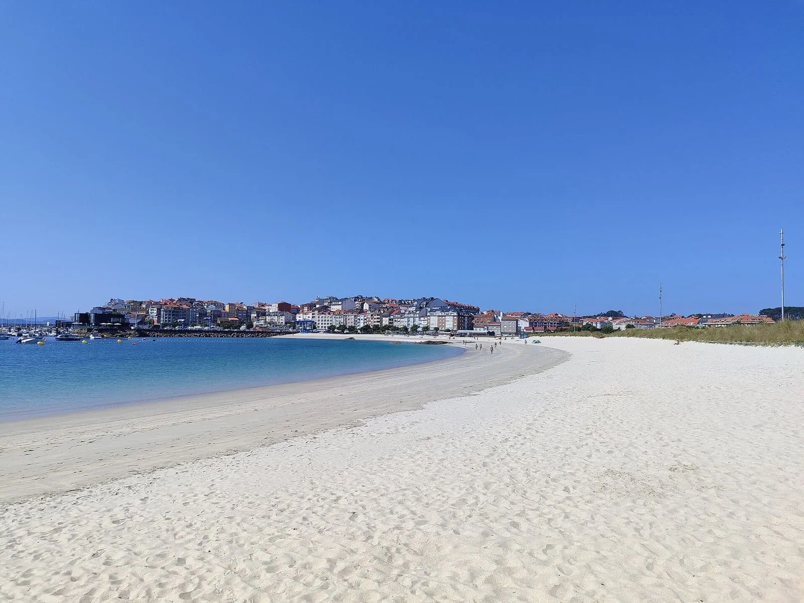 Arena blanca de la playa de Baltar con las casas de Portonovo al fondo