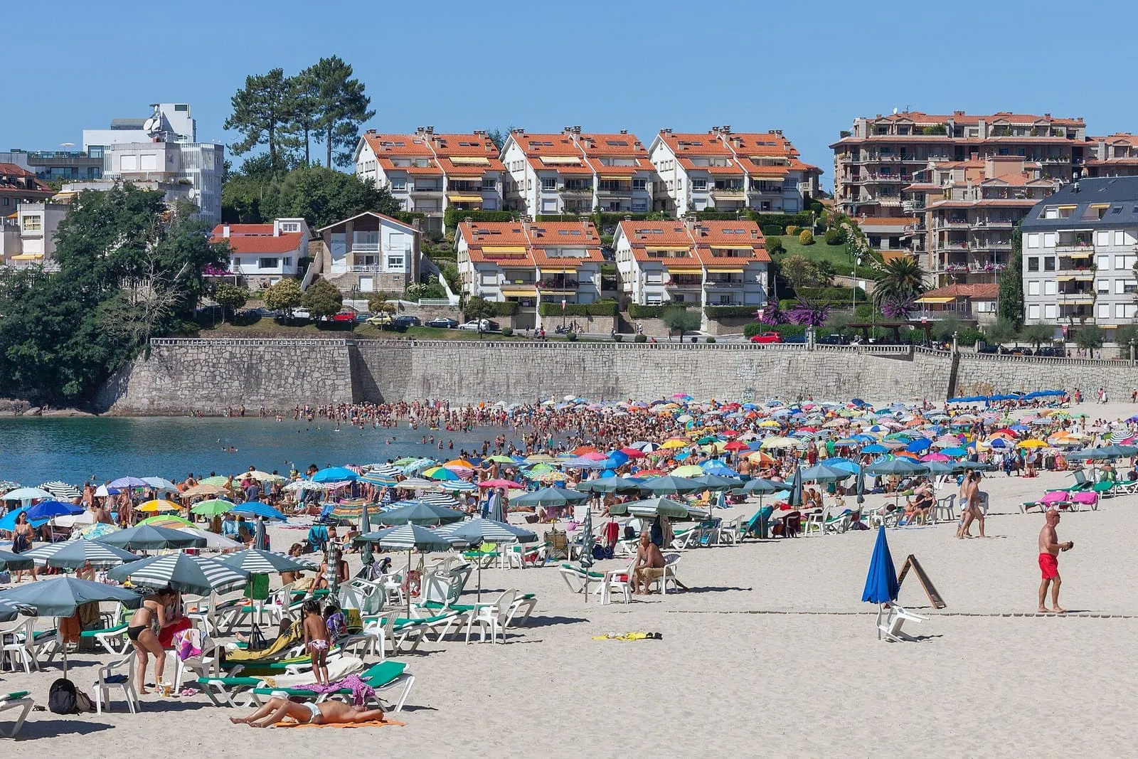 Playa de Silgar, en Sanxenxo, llena de sombrillas frente a los edificios del paseo