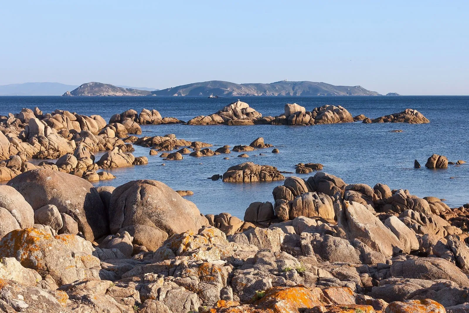 Rocas de granito en la costa de la ría de Pontevedra, con las islas Ons al fondo