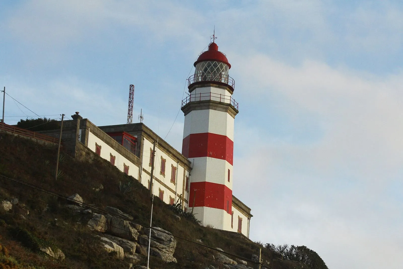 El faro de Cabo Silleiro, torre blanca y roja, junto a la casa del farero sobre el acantilado