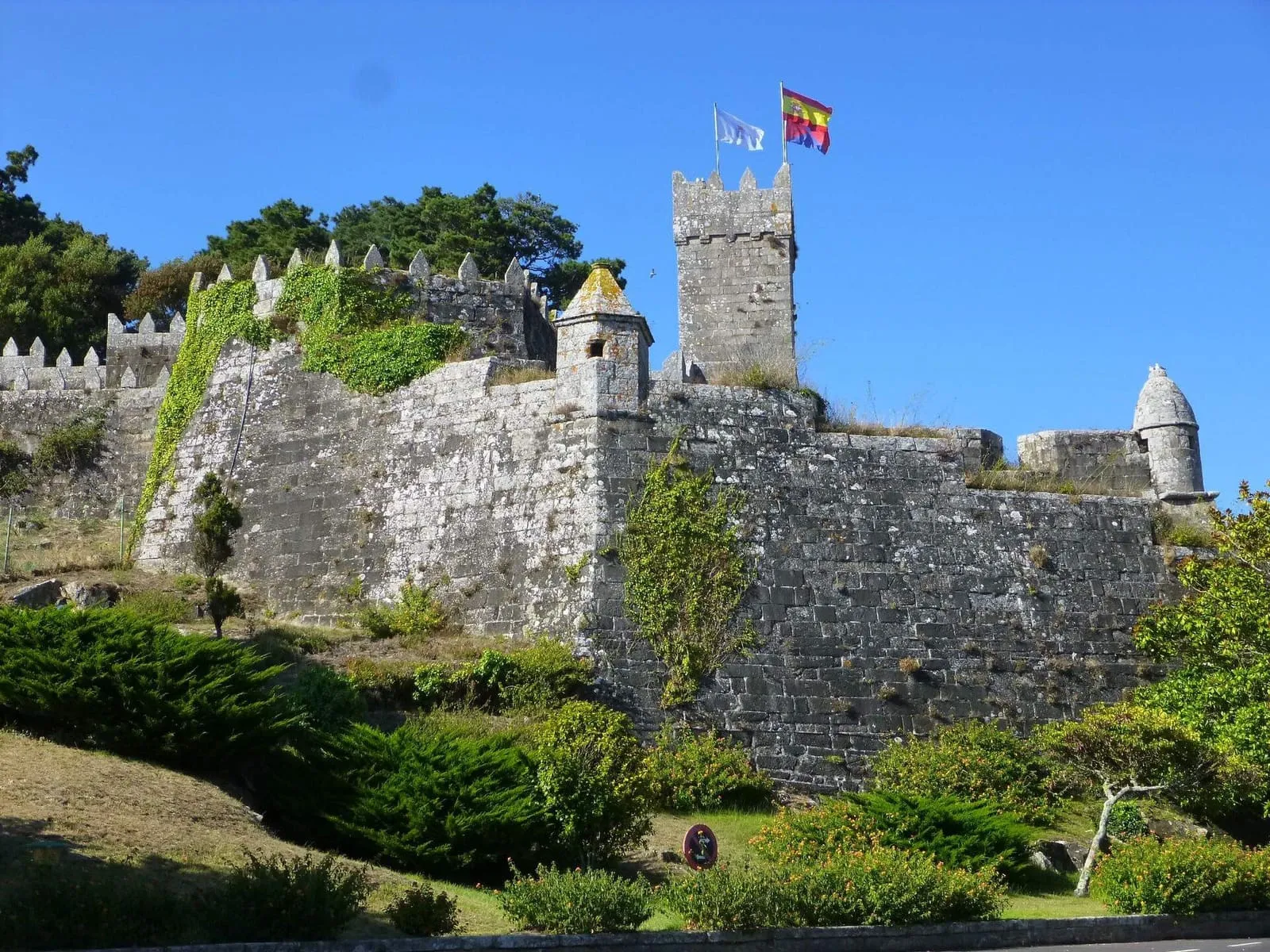 Torre y murallas de la fortaleza de Monterreal con las banderas ondeando sobre la península de Monte Boi