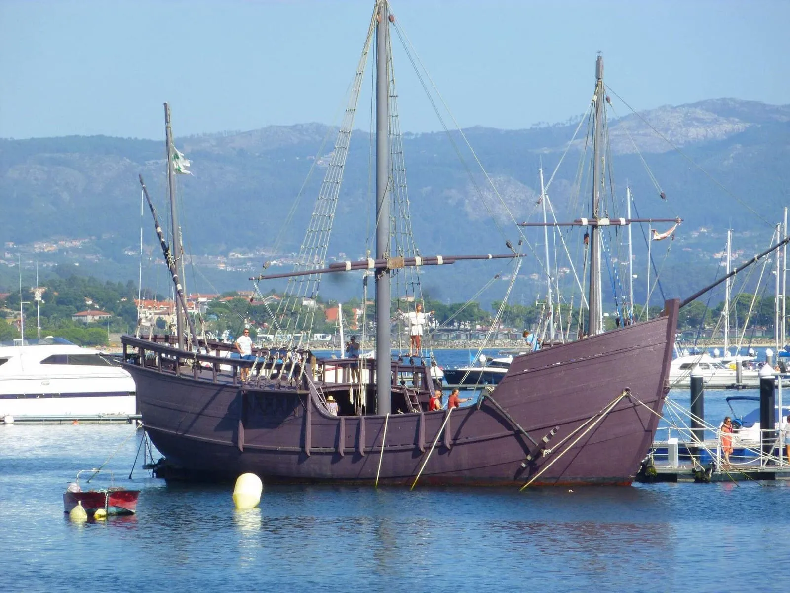 Réplica de la carabela Pinta amarrada en el puerto de Baiona, con los montes al fondo