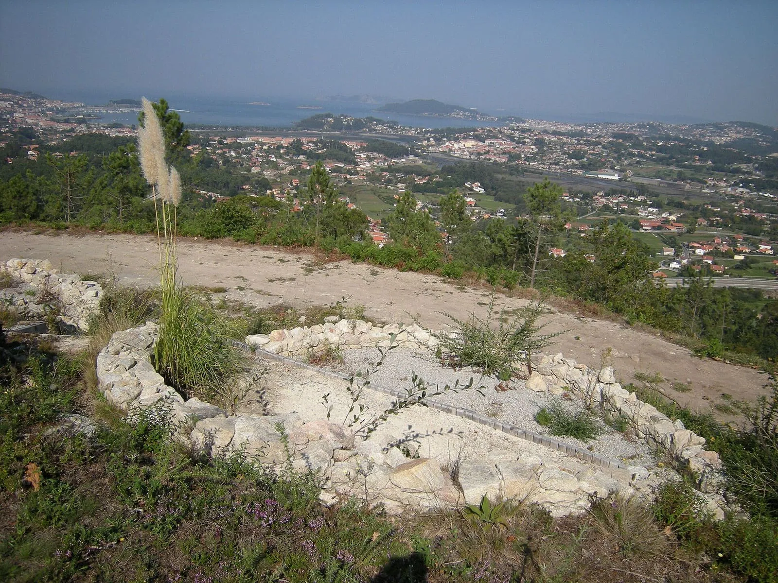 Restos circulares de piedra en el castro da Pedra Moura, con el valle del Miñor al fondo