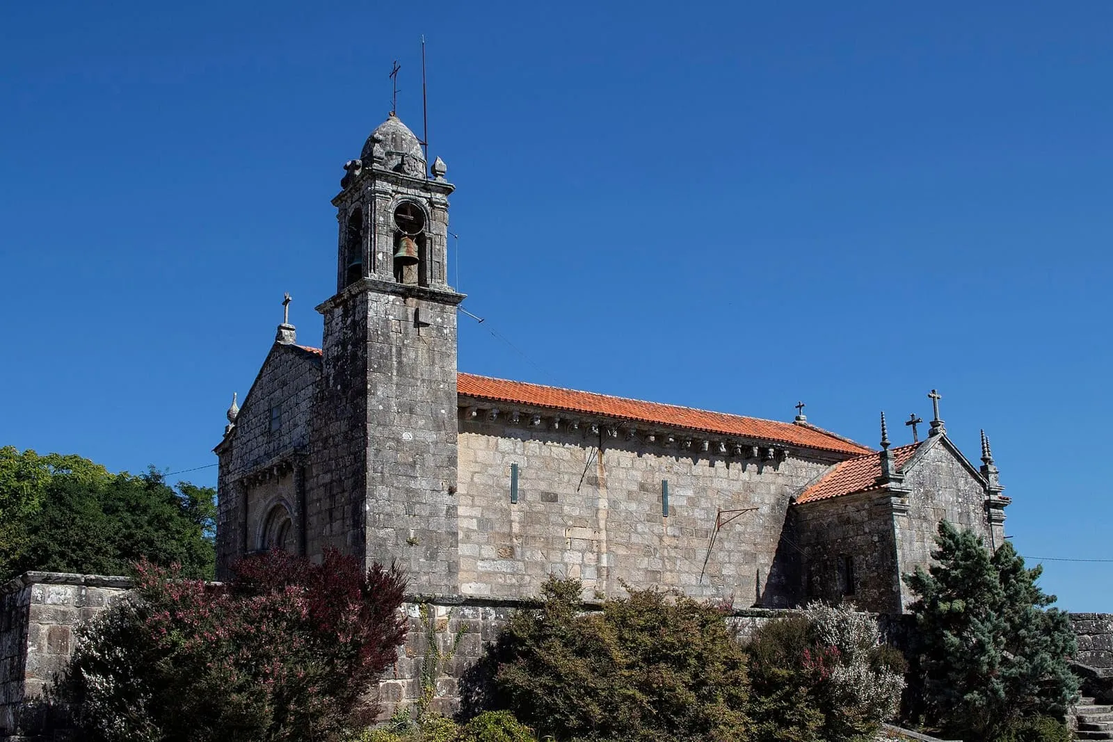 La iglesia románica de San Martiño de Moaña, de granito, con su campanario de espadaña, sobre un muro de piedra