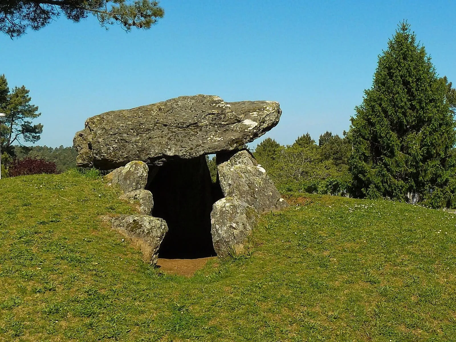 El dolmen de Meixoeiro, con una gran losa de cobertura sobre ortostatos, en un prado verde