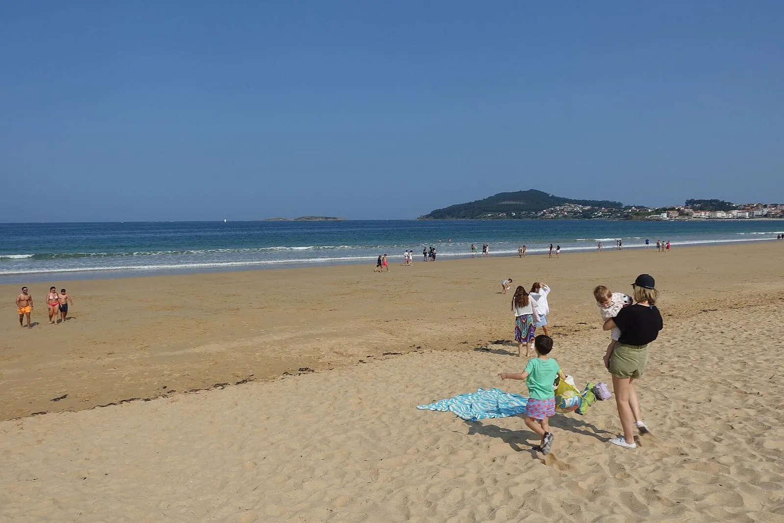 Playa América con arena dorada, familias en la orilla y el mar al fondo