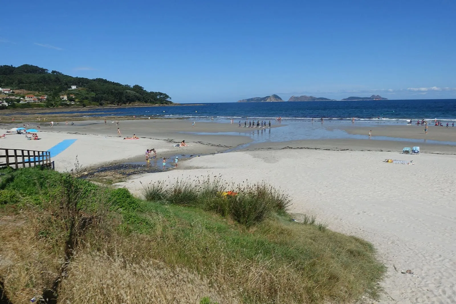Playa de Patos con arena clara, un cercado de madera y las Cíes al fondo