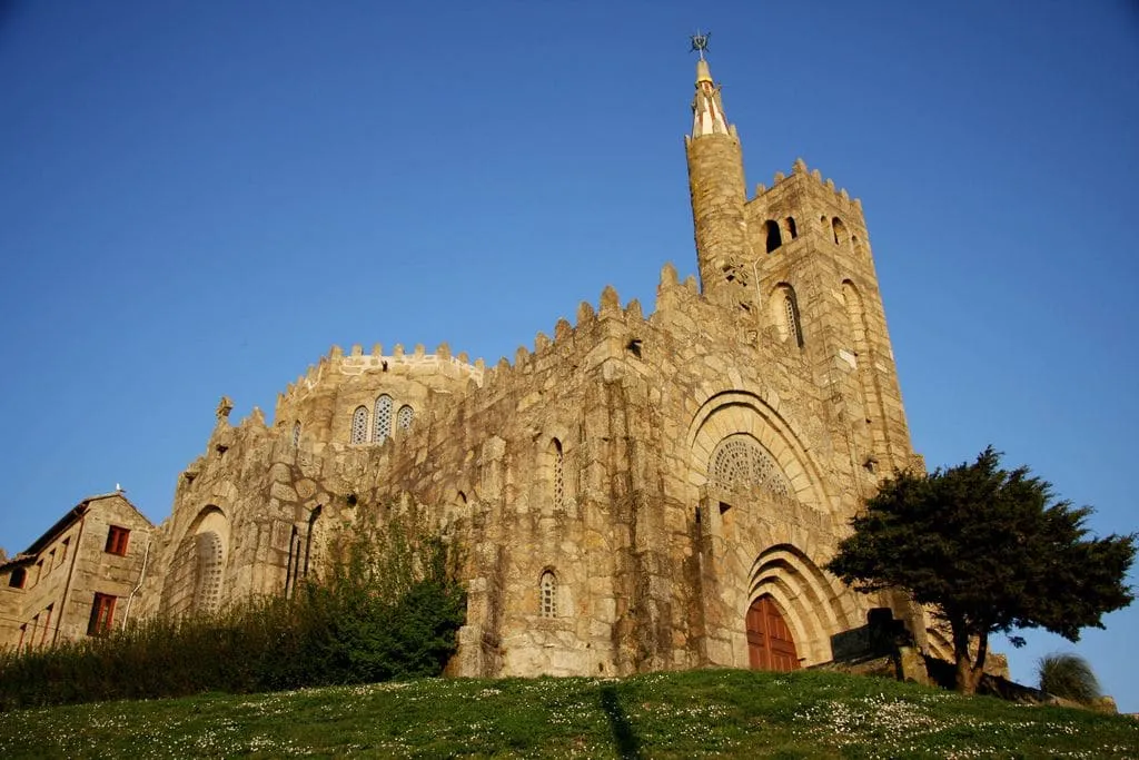 El Templo Votivo do Mar de Panxón, de granito dorado, con su torre y portadas bajo un cielo azul