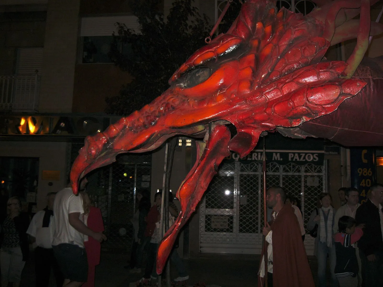 La cabeza roja del dragón de la Coca, de noche, durante el desfile de la fiesta en las calles de Redondela