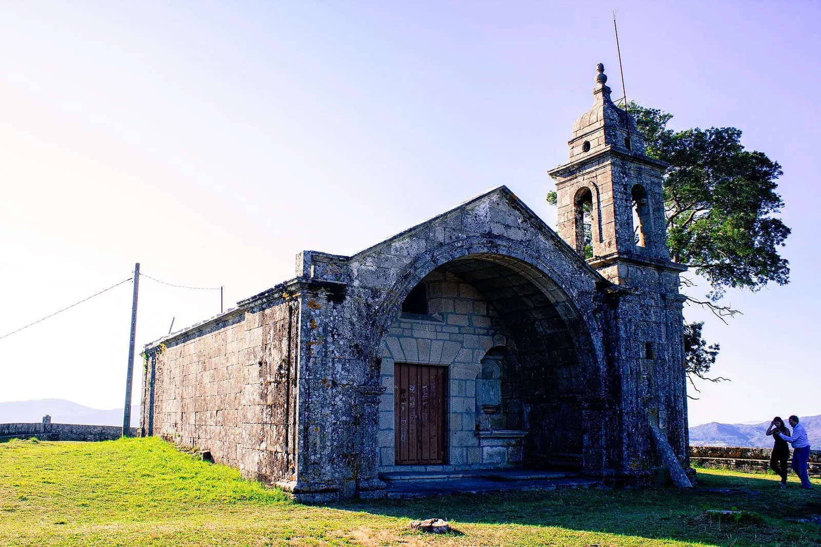 La capela da Virxe das Neves en lo alto del monte da Peneda, con arco de entrada, espadaña y la ría al fondo